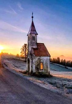 an old church sits on the side of a dirt road at sunset in rural countryside