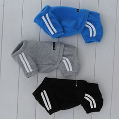 three baby clothes laid out on a white wooden floor, one blue and one black