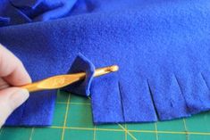 a person cutting fabric with a pair of scissors on top of the blue piece of cloth