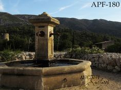 an old water fountain with mountains in the background