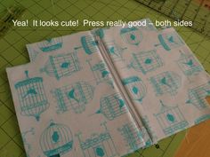 a piece of fabric with blue birds in cages on it next to scissors and cutting board