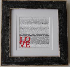 a framed book page with the word love written in red and black ink on it