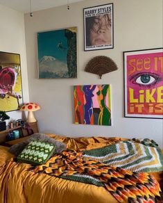 a bedroom with posters on the wall and a bed covered in an orange bedspread