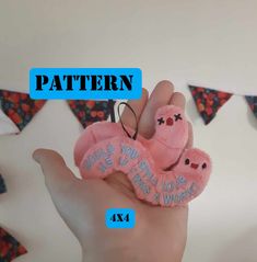 a hand holding a pink stuffed animal with the words pattern on it's fingers