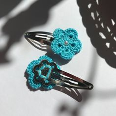 two crocheted hair combs with flowers on them sitting next to each other