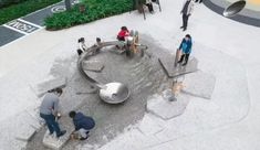 several people are gathered around a sculpture in the middle of a courtyard area, looking down at it