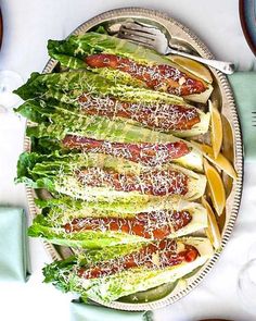 a plate with lettuce wrapped in bacon on it next to plates and silverware