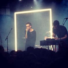 two people on stage with microphones in front of them and one person holding a keyboard