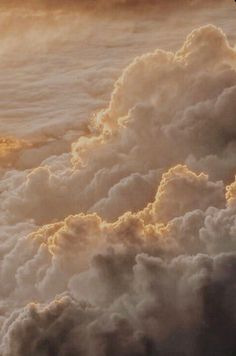 an airplane is flying through the clouds at sunset