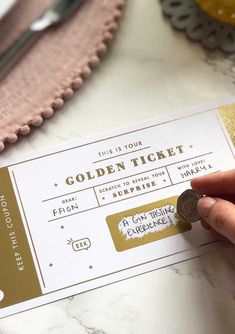 a person is holding a golden ticket on a table