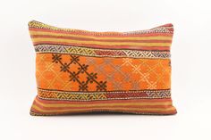 an orange and yellow decorative pillow on a white background