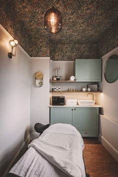 a small room with a bed, sink and cabinets