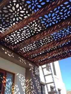 an outdoor pergolated roof with the sun shining through it and shadows on the ground