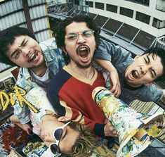 three young men with skateboards are posing for the camera