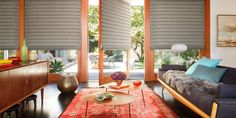 a living room filled with furniture and windows covered in blind shades on top of them