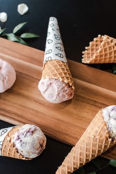 three ice cream cones sitting on top of a wooden board