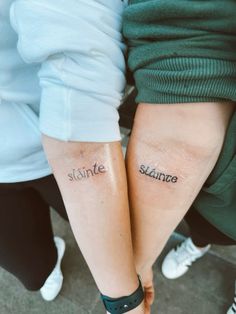 two people with matching tattoos on their arms that say sainte and sinnes, both holding hands together