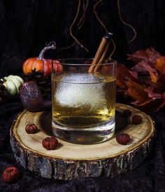 a glass filled with liquid sitting on top of a wooden slice