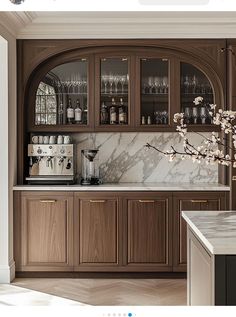 a kitchen with marble counter tops and wooden cabinetry, along with wine glasses on the shelves