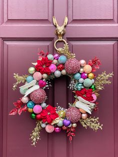 a pink door with a christmas wreath hanging from it's side and decorations on the front