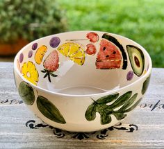 a bowl with fruit painted on it sitting on a table