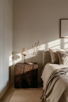 a bed sitting next to a window in a room with white walls and wooden furniture