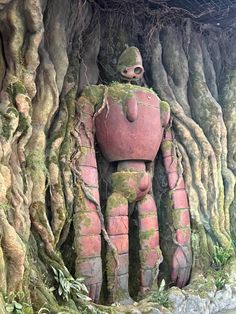 there is a statue that looks like a man in the woods with trees growing around it