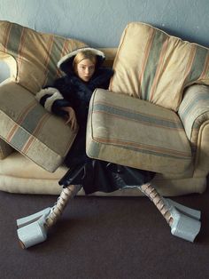 a woman sitting on top of a couch covered in pillows