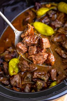 a spoon full of meat and peppers in a slow cooker