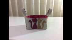 a small basket with two spoons in it sitting on a table next to a curtain