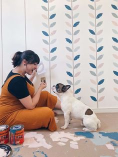 a woman sitting on the floor playing with her dog