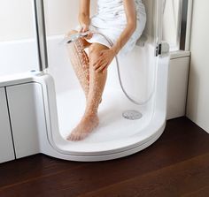 a woman is sitting in the shower with her legs up