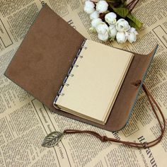 an open notebook sitting on top of a table next to flowers and a bookmark