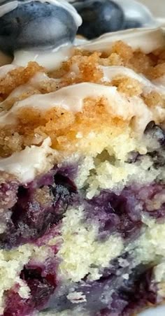 a close up of a piece of cake on a plate with blueberries and cream