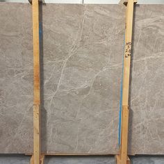 two gray marble slabs sitting next to each other on wooden frames with blue tape around them