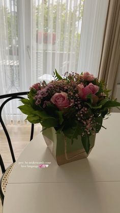 a bouquet of pink flowers sitting on top of a white table next to a window