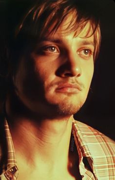 a close up of a person wearing a plaid shirt and looking at the camera with an intense look on his face