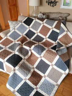 a couch with a blanket on top of it in a living room next to a lamp