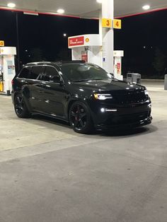 a black car parked in front of a gas station