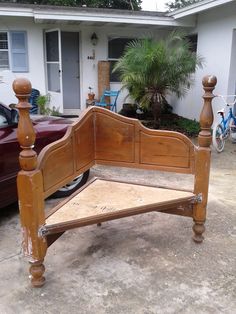 a wooden bed frame sitting in front of a house next to a parked car on the sidewalk