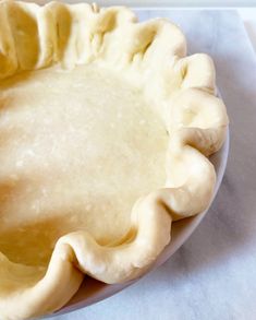 an uncooked pie crust sitting on top of a white tablecloth covered plate