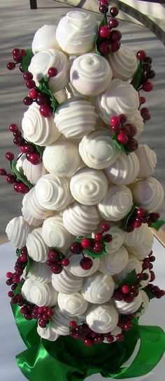 a white cake with red berries and green ribbon