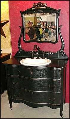 an antique dresser with mirror and sink in front of red wallpapered room area