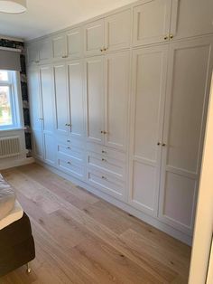 an empty bedroom with white cupboards and wood flooring on the side of the room