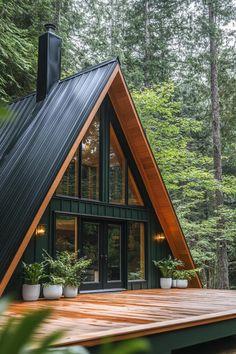 a - frame cabin in the woods with wood decking and potted plants on the porch