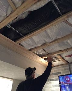 a man standing in front of a flat screen tv on top of a wooden frame