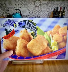 someone holding up a box of fried fish nuggets