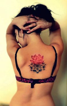 a woman's back with a tattoo on her body and a pink flower in the center