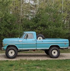 an old blue pickup truck parked in front of some trees