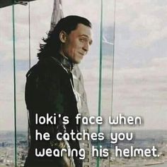 a man standing in front of a glass window with the words loki's face when he catches you wearing his helmet